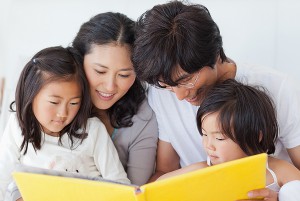 A close up shot of the family sitting on the bed and reading a story book; Shutterstock ID 244463917